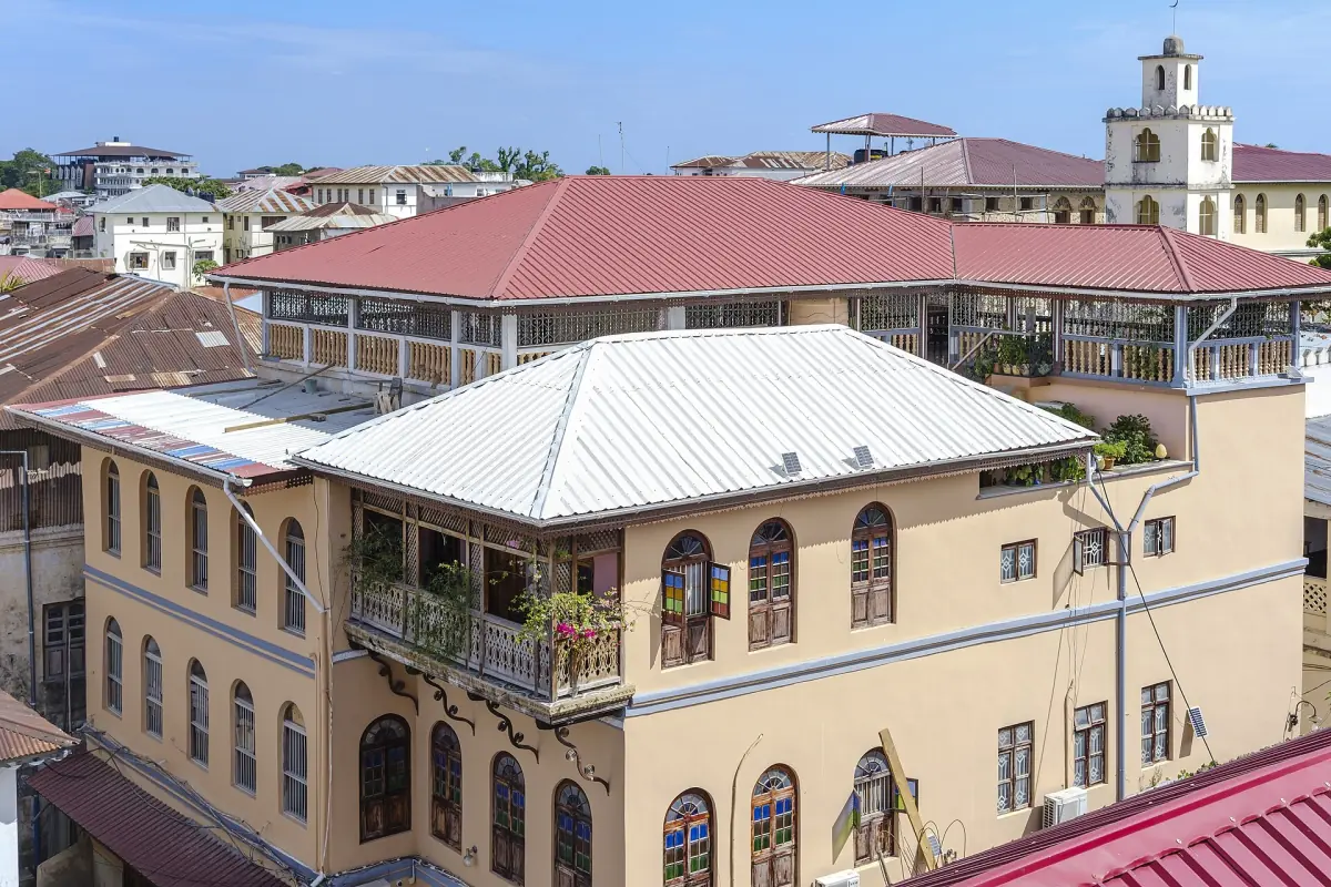 Rooftops and balconied houses of Stone Town with a clock tower behind