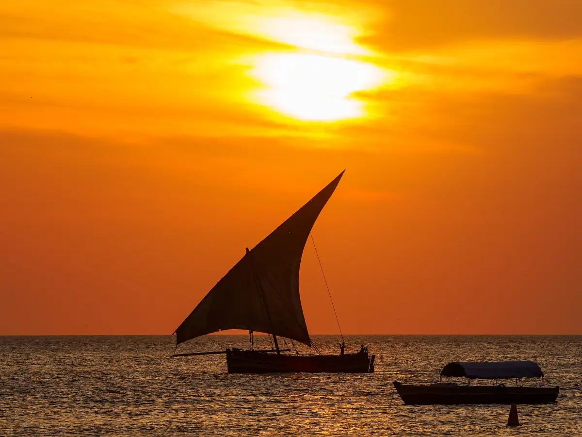 Dhow sailing boat in silhouette against an orange sunset