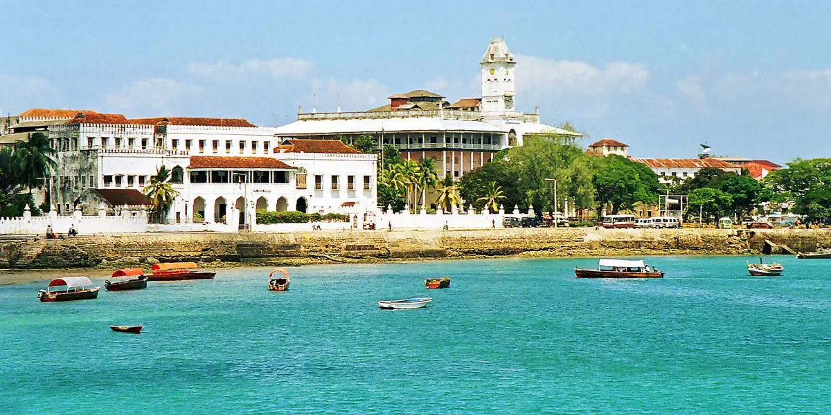 Waterfront von Stone Town mit dem House of Wonders und Booten auf türkisem Wasser