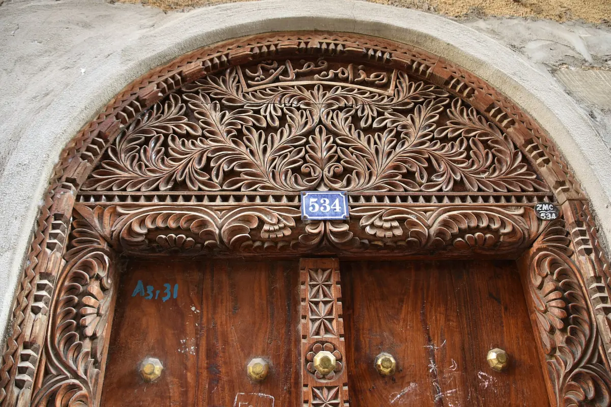 Geschnitzte Holztür mit verziertem Bogen darüber in Stone Town